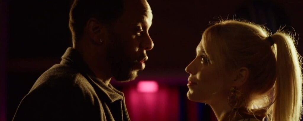 Still from Freak Off which shows Ricky Burchell and Ayla Demirci standing opposite each other, talking.