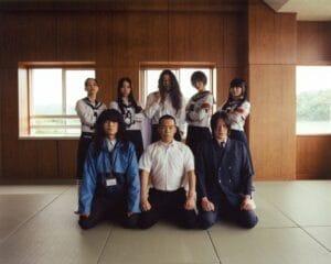 Group photo of Balming Tiger and ATARASHII GAKKO! posing together where three people are kneeling on the floor and five people stand behind them.