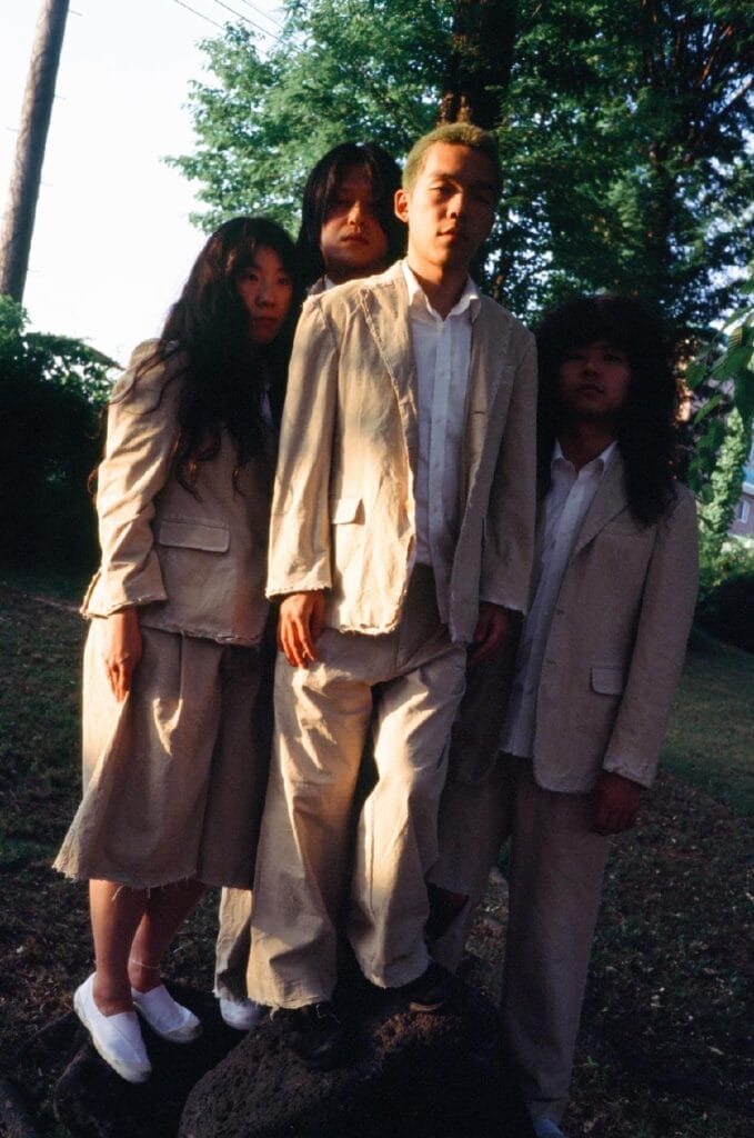 Press photo of Balming Tiger in a forest wearing beige suits.