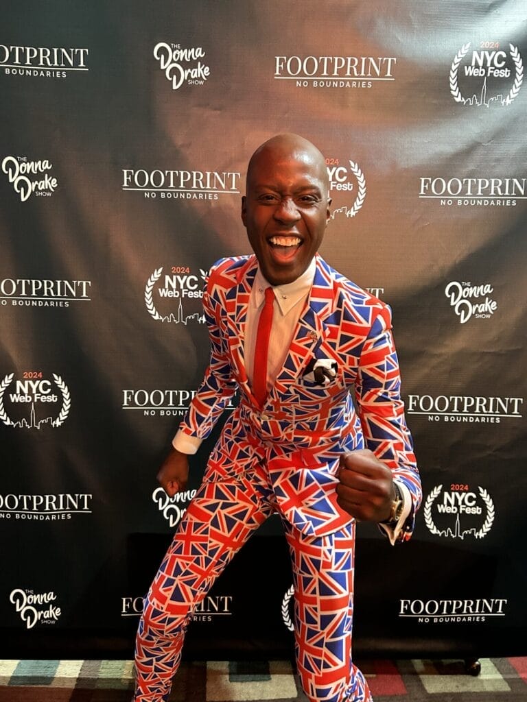 Photo of Charlii Sebunya, wearing a snazzy suit, on the red carpet at the NYC Web Fest 2024.
