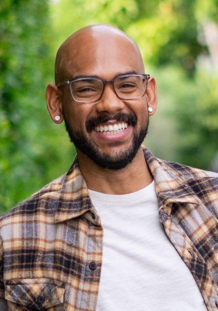 EXCLUSIVE: NYC Web Fest 2025 Announces Jury Line-Up and Welcomes Podcasts as New Category 81 Head shot photo of Todd A. Jackson with greenery behind him. He's smiling at the camera, wearing glasses, a brown-and-white checkered shirt which is open with a white top underneath.