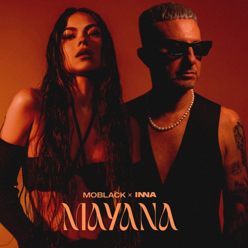 Official single cover artwork for "Mayana" which is filtered to a dark orange-brown colour and sees INNA looking sultry in a black bra with straps paired with black gloves, while MoBlack is cropped in behind and to the right of her, wearing a black waistcoat, a silver necklace and a pair of shades, looking to the right.