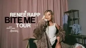 Official BITE ME Tour image which sees Reneé Rapp kneeling on a bed wearing a white vest top under a fur coat while holding an old cord telephone to her ear. Her blonde hair is in a wet style and the tour's name is shown on the left in front of the beige-pink curtains.