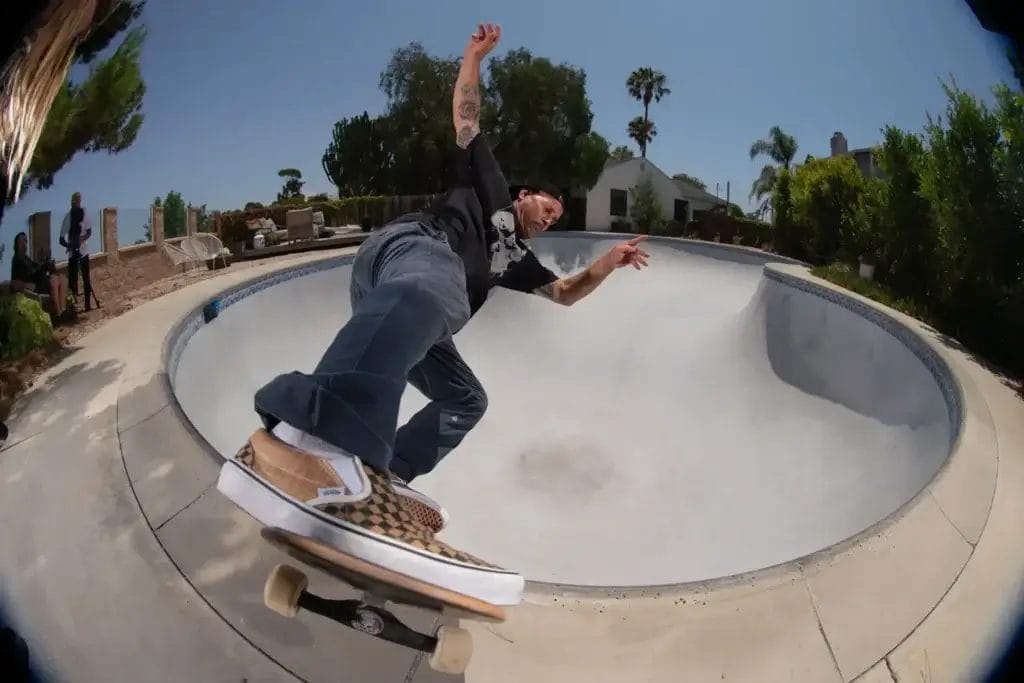 Omar Hassan riding a skateboard in his own skating rink while wearing the Signal and Ernest Packaging cardboard Vans Slip-On sneakers.