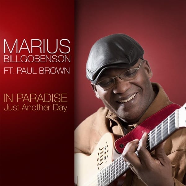 The second official single cover artwork for "In Paradise – Just Another Day" which has the same red background and same text on the left, but there's a different image of Marius Billgobenson which is a mid-shot showing him playing a guitar and smiling down at it.