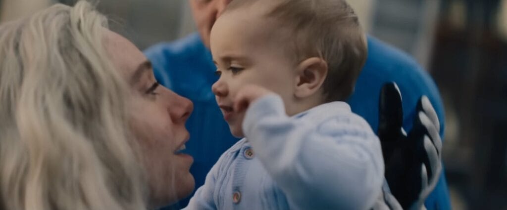 Still from the official trailer to The Fantastic Four: First Steps, which shows Sue Storm holding up her baby son and slowly bringing him towards her for a kiss.