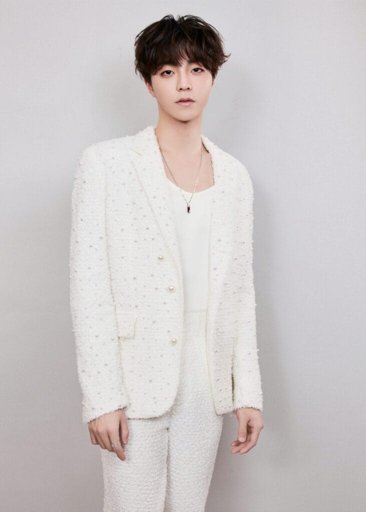 Chen Linong posing for a professional photo, wearing a pristine white suit.