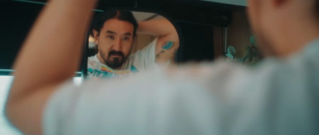 Still from the "Everytime We Touch" music video which sees Steve Aoki looking at himself in the mirror after getting ready to go up to the top deck and join Cascada.