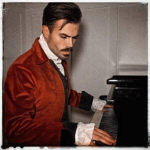 Official single cover artwork for "My Composer" which shows Samuel Warburton sat at a piano with his hands placed on the key cover, ready to lift it to expose the keys. He is wearing a white shirt with a burgundy coloured jacket.