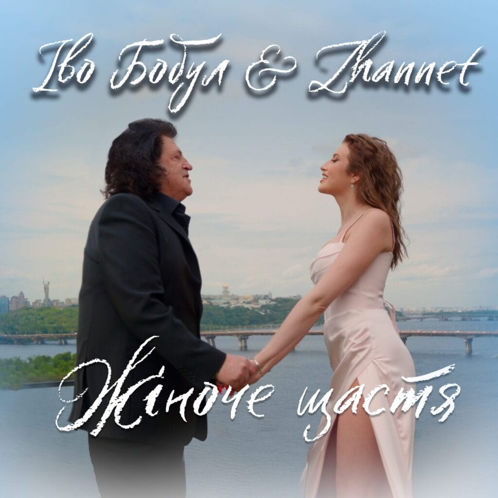 Ukrainian Singer ZHANNET on Viral Success of “Women’s Happiness” Duet With Ivo Bobul and Her TikTok Transformation 19 Official single cover artwork for "Women's Happiness" which shows Ivo Bobul and ZHANNET holding hands by a river with a city skyline and bridge in the background. The scene is romantic, featuring Ivo Bobul in a suit and ZHANNET in a light cream dress. Text in Cyrillic script overlays the image.