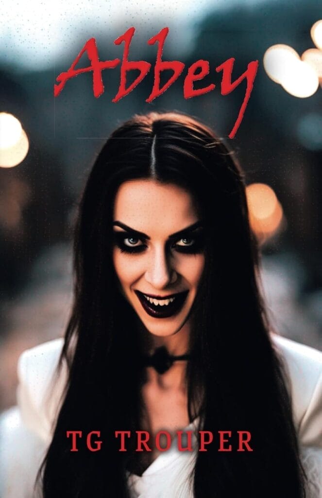 Creepy book cover with a sinister vampire woman dressed in white, sporting dark makeup and a chilling grin. The title "Abbey" is in red above her, evoking a gothic vibe whilst text stating TG Trouper is below also in red.