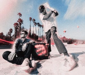 MOVIESTARZ at the beach; one member of the duo sits relaxed next to a glowing TV with red text, the other swings a bat. Surreal colours and palm trees create a dynamic vibe.