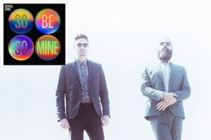 Capital Cities in suits with a bright, overexposed background. Both wear sunglasses, projecting a cool and confident vibe. Colourful circular text is the official single cover artwork which is overlayed in the top-left corner which reads "SO BE SO MINE".