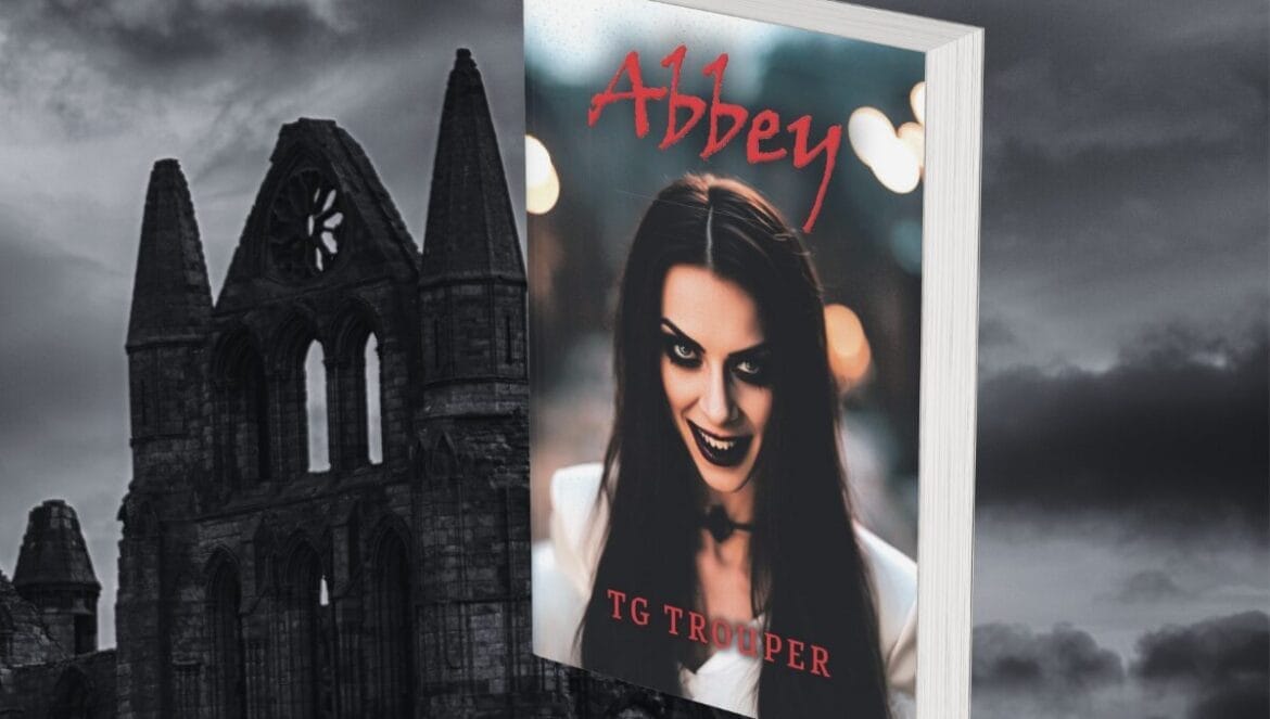 A book titled "Abbey" by TG Trouper with a vampire woman on the cover, set against a dramatic, dark sky and a gothic-style, Whitby Abbey.