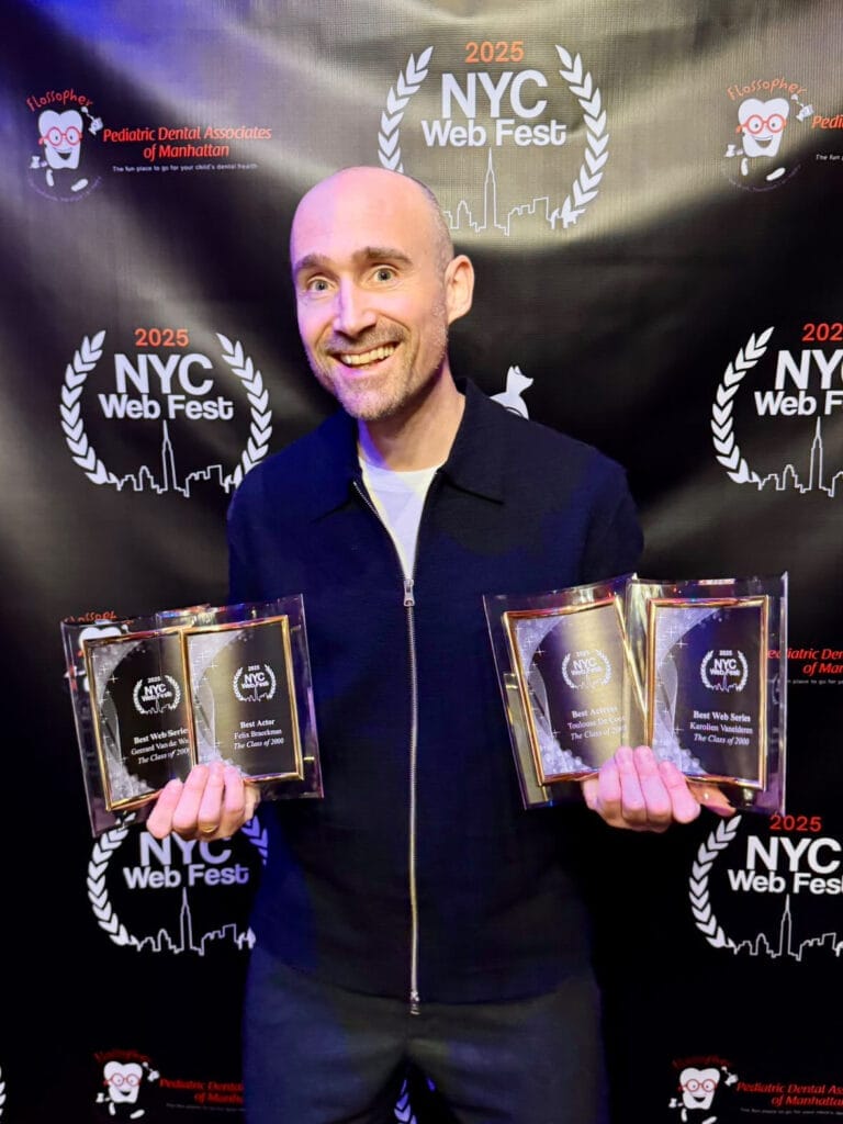 Geerard Van de Walle stands smiling, holding four awards at the 2025 NYC Web Fest, in front of a black backdrop with festival logos and sponsor details.