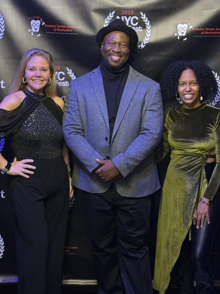 Zerelda Nothnagel, Karlton T. Clay, and MelimeL smiling in evening attire stand in front of a black backdrop with "NYC Fest 2025" logos. The mood is celebratory and formal.