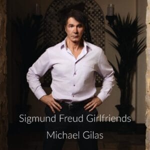 Official single cover artwork for "Sigmund Freud Girlfriend" which shows Michael Gilas in a light white shirt standing confidently with hands on hips in a dimly lit room. The song's title and the artist name is overlaying the image in white text at the bottom.